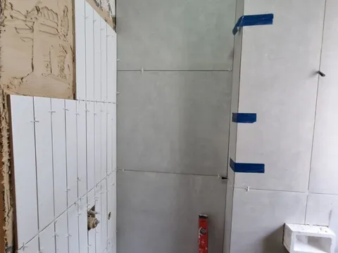 עבודות חיפוי קיר בשלב הביניים של שיפוץ מקלחת האורחים