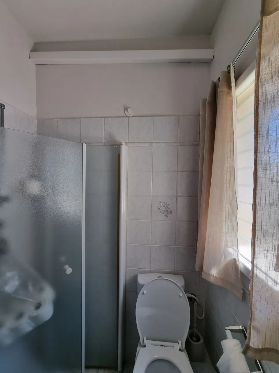 מקלחון זכוכית מחוספסת ואסלה ישנה בחדר המקלחת לפני תחילת העבודות