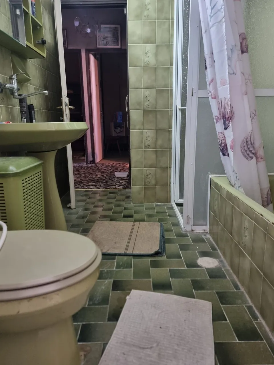 מקלחת בחיפוי אריחים ירוקים מיושנים לפני השיפוץ