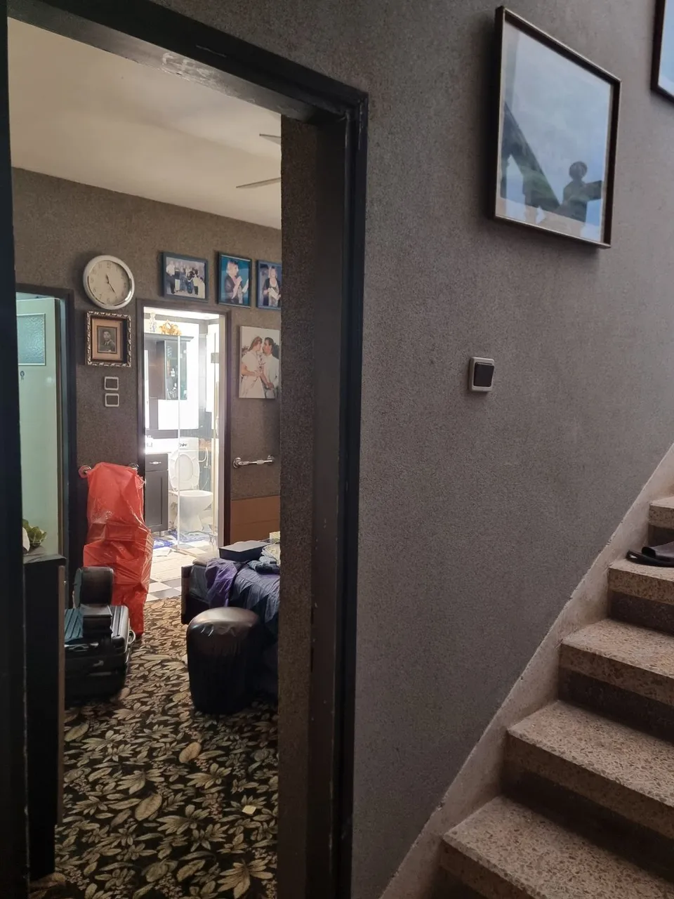 מבואה ישנה עם תמונות משפחתיות ומדרגות לפני השיפוץ