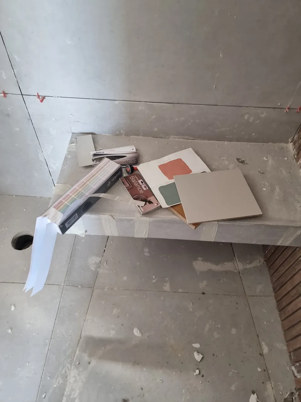 דוגמאות צבע וחיפוי מונחות על אדן בטון באתר השיפוץ