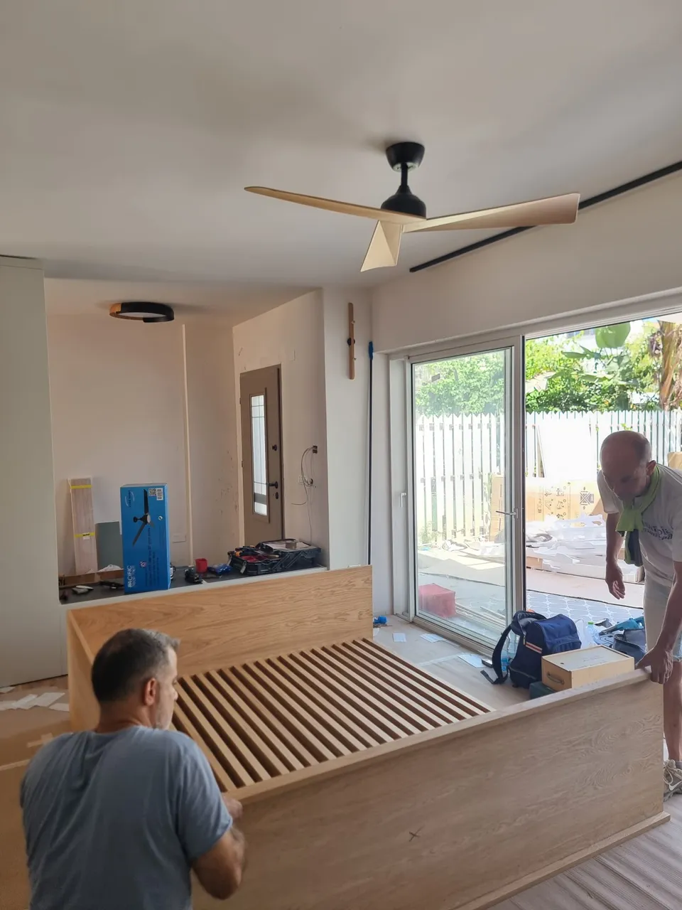 התקנת מיטת עץ מובנית וגוף תאורה מעוצב בחדר השינה