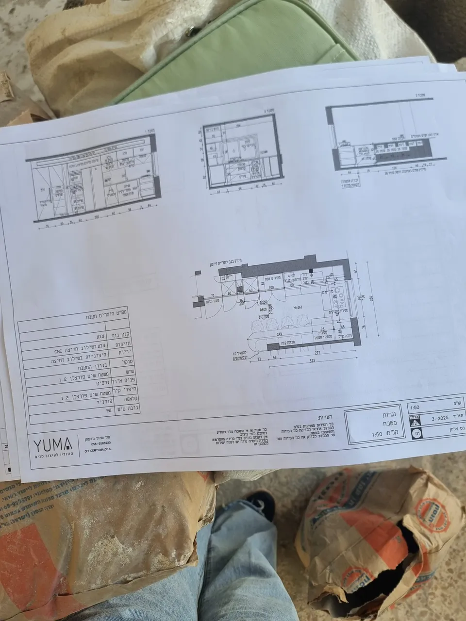 תוכניות בנייה מונחות על שקי מלט באתר הבנייה בהרצליה