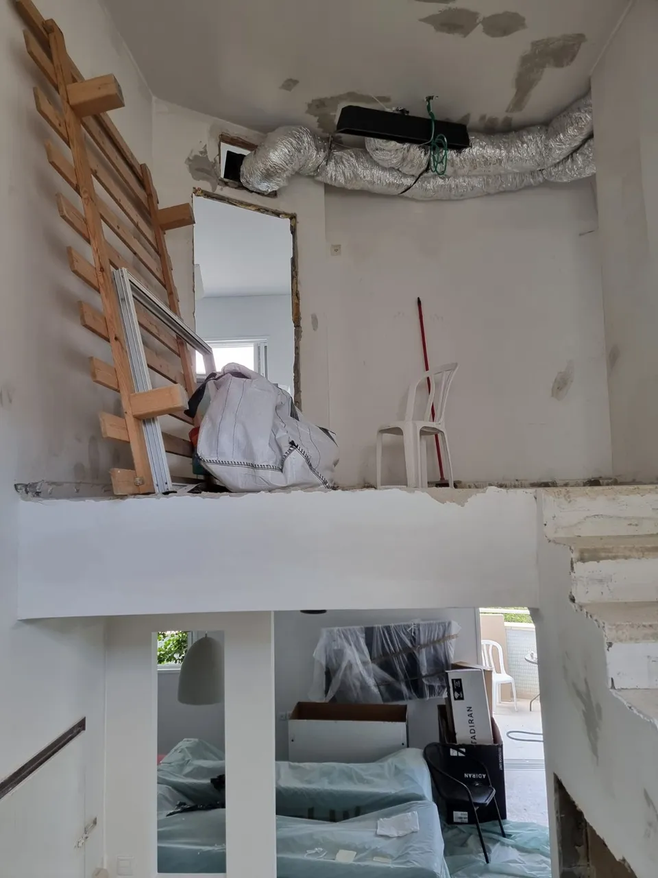 אזור אחסון עליון בעיצומו של השיפוץ עם סולם עץ וריהוט עטוף בניילון